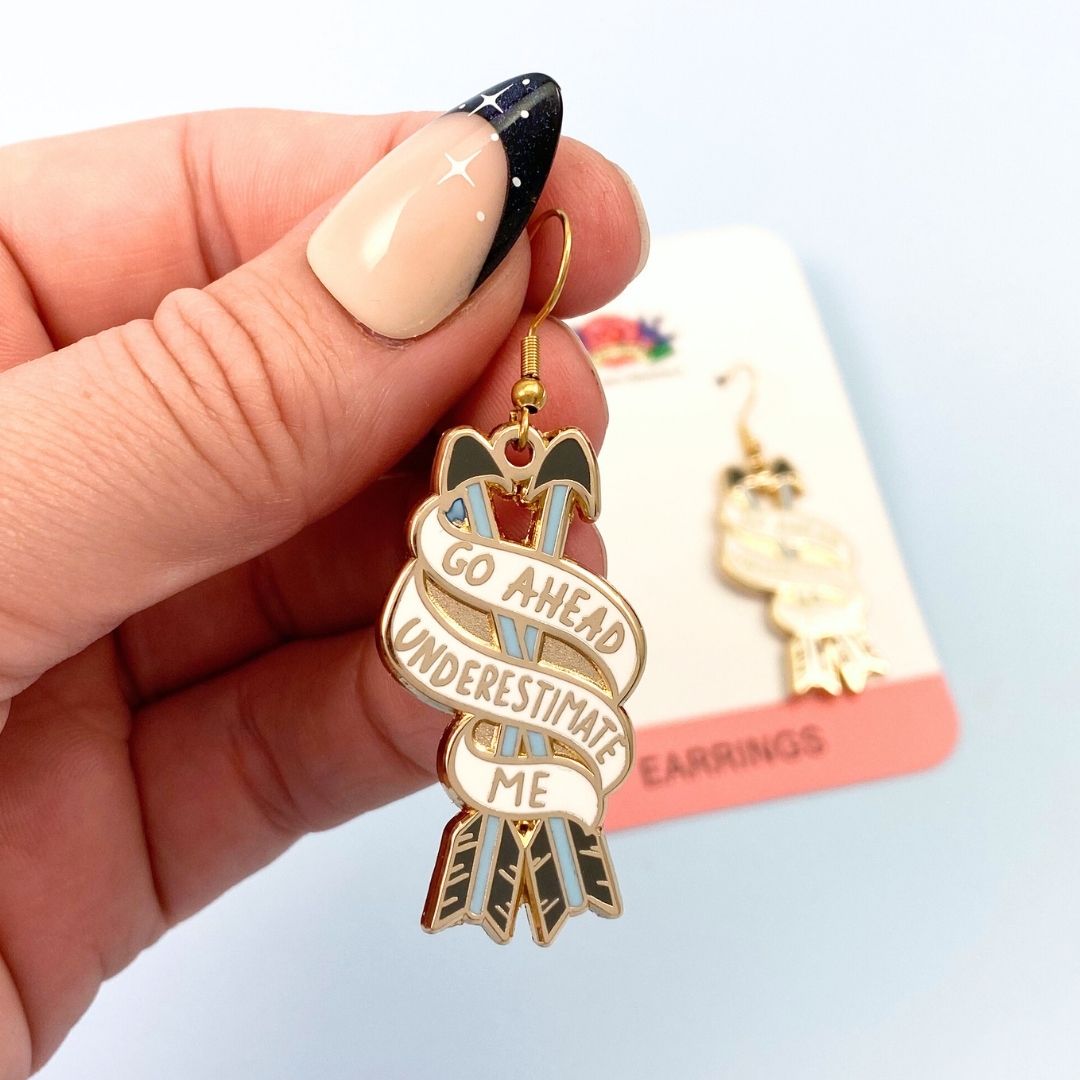 Go ahead underestimate me earrings - one being held, one on bscking card in background